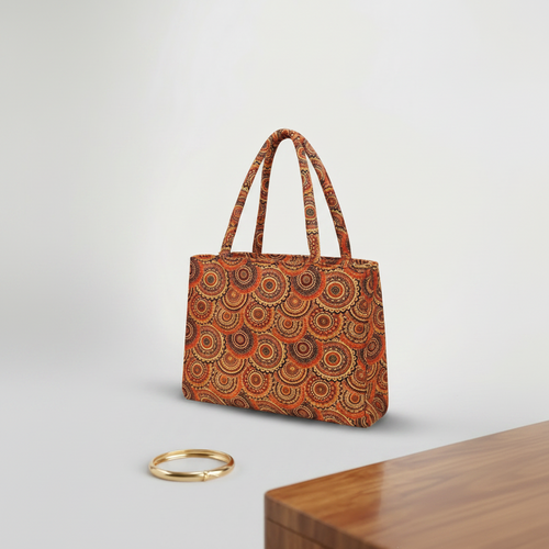 Patterned handbag on a light gray background with a wooden surface and gold ring.